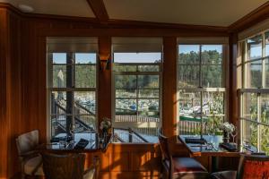 a dining room with windows and tables and chairs at Noyo Harbor Inn in Fort Bragg