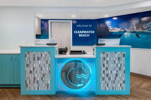 a welcome desk in a room with a blue wall at Winter the Dolphins Beach Club, Ascend Hotel Collection in Clearwater Beach