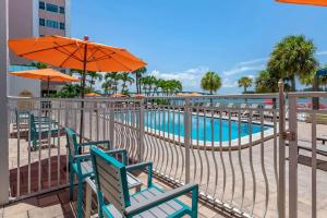 a pool with chairs and umbrellas next to a fence at Winter the Dolphins Beach Club, Ascend Hotel Collection in Clearwater Beach