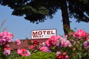 ein Schild für ein Motel neben rosa Blumen in der Unterkunft Motel West in Bend