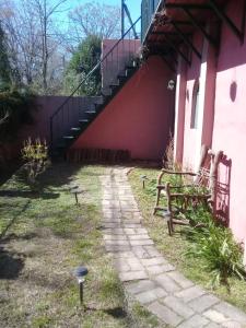 una pasarela junto a un edificio rosa con una escalera en Posada Don Salvador en San Antonio de Areco