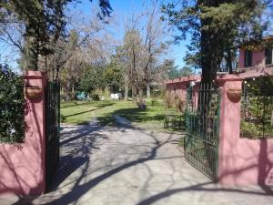 an open gate to a yard with trees at Posada Don Salvador in San Antonio de Areco