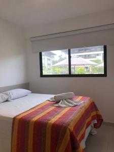 um quarto com uma cama com um cobertor e uma janela em Cupe Beach Living Flat em Porto de Galinhas