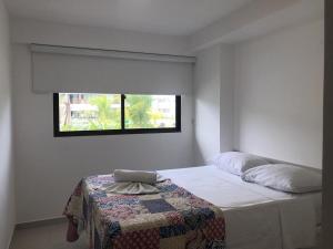 una camera da letto con un letto con una coperta e una finestra di Cupe Beach Living Flat a Porto De Galinhas
