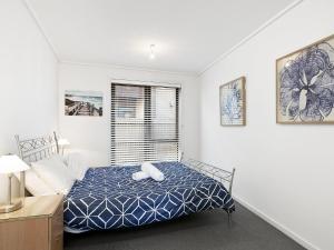 a white bedroom with a bed and a window at Apartment 26 Pacific Apartments in Lorne