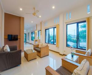 a living room with couches and a tv and windows at Citrus-House com Hotel in Bogor
