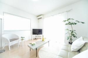 Sala de estar blanca con sofá blanco y mesa en Yokkaichi Hazunaka Hotel en Yokkaichi