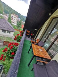 una casa con balcón con mesa de madera y sillas. en Apartament Kalinderu K1 Bușteni, en Buşteni