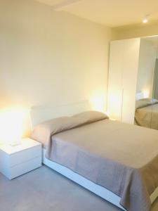 Schlafzimmer mit einem weißen Bett und einem Spiegel in der Unterkunft YOUR HOME MILANO Bellinzago Lombardo in Bellinzago Lombardo