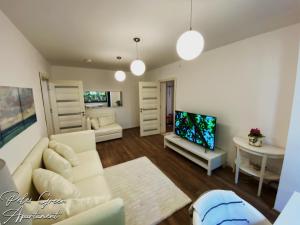 a living room with a white couch and a tv at Peles Green Apartment in Cluj-Napoca