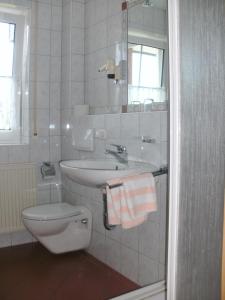 a white bathroom with a sink and a toilet at Pension zur Traube 3 Sterne in Oberschwarzach