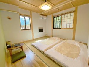 a bedroom with a bed and a table and two windows at Toraya in Gero