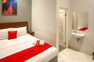 a bedroom with a bed and a bathroom with a sink at RedDoorz Syariah At Pucang Anom in Surabaya