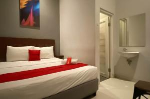 a bedroom with a bed with a red blanket and a sink at RedDoorz Syariah At Pucang Anom in Surabaya
