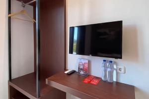 Zimmer mit einem Holzregal und einem TV an der Wand in der Unterkunft RedDoorz Syariah At Pucang Anom in Surabaya