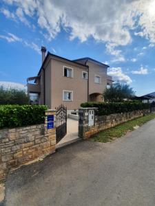 a house with a stone fence and a driveway at Apartment and Room Marlen in Rovinjsko Selo