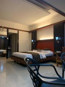 a hotel room with two beds and a chair at Honeybee Resort in Lonavala