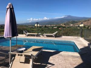 a swimming pool with an umbrella and two chairs and a table at Villino Lenci in Trappitello
