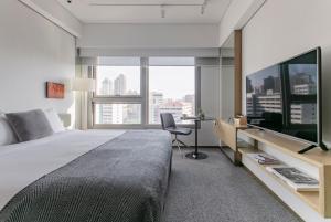 een slaapkamer met een groot bed en een bureau met een televisie bij Hotel Stage in Hong Kong