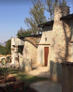 a stone house with a brick chimney and a door at Damascus Bush Lodge in Hartbeespoort