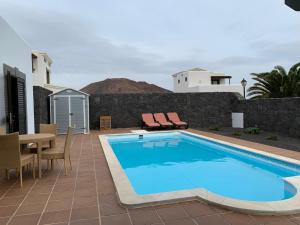 a pool with a table and chairs next to a building at Villa Denise in Yaiza