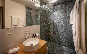 La salle de bains est pourvue d'un lavabo et d'une douche. dans l'établissement The Hide Apartments, à Flims