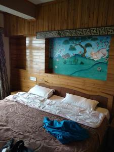 ダージリンにあるHotel Taktsang Darjeelingのベッドルーム1室(壁に絵画が描かれたベッド1台付)