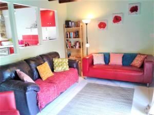 una sala de estar con 2 sofás de cuero y un sofá rojo. en Gites at La Maison Sans Souci, en Le Guislain