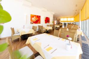 格莱斯多夫Business Hotel Ambio Gleisdorf的餐厅配有白色的桌椅和墙上的绘画作品
