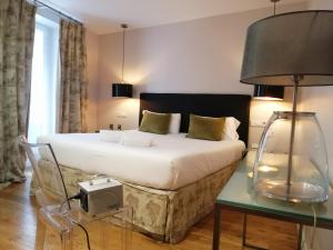 Un dormitorio con una cama y una mesa con una lámpara. en Hotel Cuéntame La Puebla, en Burgos