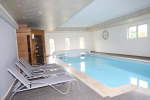 een groot zwembad met stoelen in een kamer bij Gîtes La Cigale et Le Grillon in Bouillon