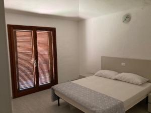 a bedroom with a bed and a window with shutters at Residenze Gambaru in San Teodoro