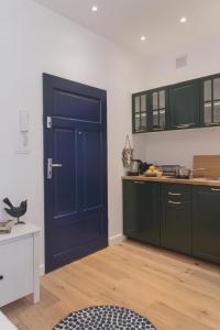 uma cozinha com uma porta azul e armários verdes em Hornigold Katowice Nikiszowiec em Katowice