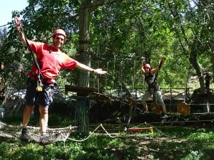 Due uomini in piedi su una zip line tra gli alberi di Agriturismo San Cataldo a Motta Camastra