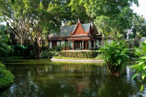 ein Haus mit einem Teich vor einem Haus in der Unterkunft Chiva-Som International Health Resorts in Hua Hin