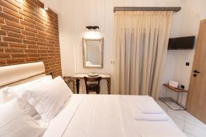 カランバカにあるOikion Meteora Home 2の白いベッドとレンガの壁が備わるベッドルーム1室が備わります。