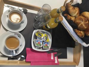 une table avec deux tasses de café et une assiette de nourriture dans l'établissement Hôtel Verone - Liège Centre, à Liège