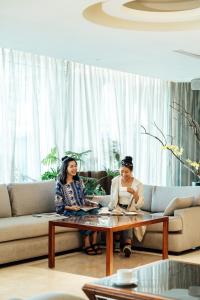 Dos mujeres sentadas alrededor de una mesa de café en una sala de estar en Arsma Hotel en Hualien