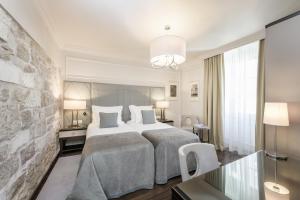 um quarto com uma cama grande e uma parede de pedra em Bastion Heritage Hotel - Relais & Châteaux em Zadar