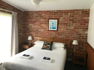 1 dormitorio con cama y pared de ladrillo en Prom Coast Holiday Lodge en Waratah Bay