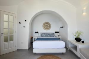 um quarto branco com uma cama e uma porta branca em Filotera Suites em Oia