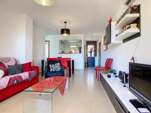 uma sala de estar com um sofá vermelho e uma televisão em Albatros Playa 3 - 4908 em Mar de Cristal