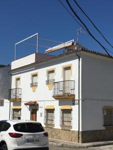 una casa blanca con un coche aparcado delante de ella en Casa Sinclair, en El Colmenar