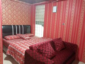 - une chambre rouge avec un lit et un canapé dans l'établissement Mayestik Guest House Syariah, à Jakarta