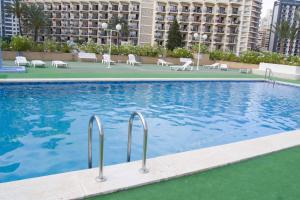 a large swimming pool with chairs and a building at Paraiso XI 1 Alquilevante in Benidorm