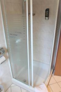 La salle de bains est pourvue d'une douche avec une porte en verre. dans l'établissement Apartment Hotel, à Henstedt-Ulzburg