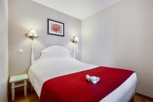 a bed with a red blanket and two candles on it at Résidence Pierre & Vacances La Villa Maldagora in Ciboure