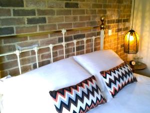 a bed with two pillows on it with a brick wall at The Green Man Boutique Hotel in Takeley