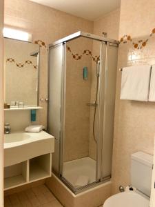 een badkamer met een douche, een wastafel en een toilet bij Thermal Hotels & Walliser Alpentherme Leukerbad in Leukerbad