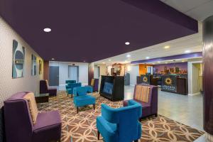 a waiting room with blue chairs and a bar at La Quinta by Wyndham Memphis Airport Graceland in Memphis